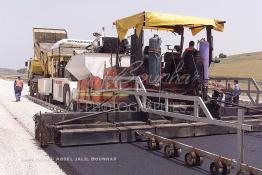 Image du Maroc Professionnelle de  Travaux sur la voie en construction Sidi el Yamani-Asilah installation de la première épaisseur de la couche de revêtement de la chaussée, Mercredi 12 Juin 2002. (Photo / Abdeljalil Bounhar) 